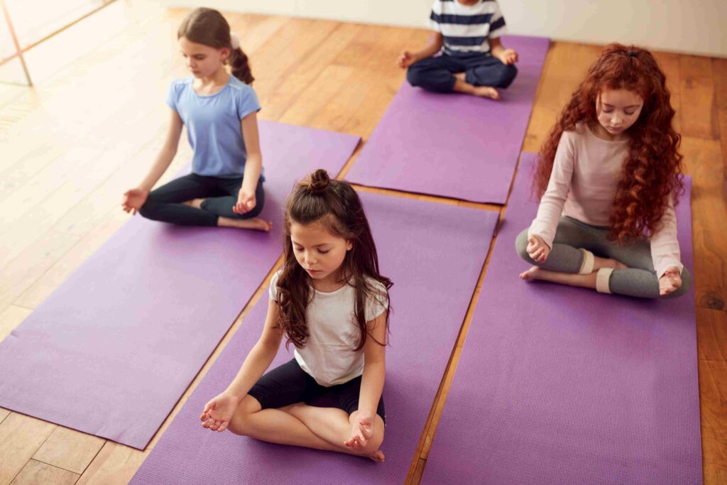 Anasınıfı öğrencileri yoga matları üzerinde mindfulness ve meditasyon uygulaması yaparken
