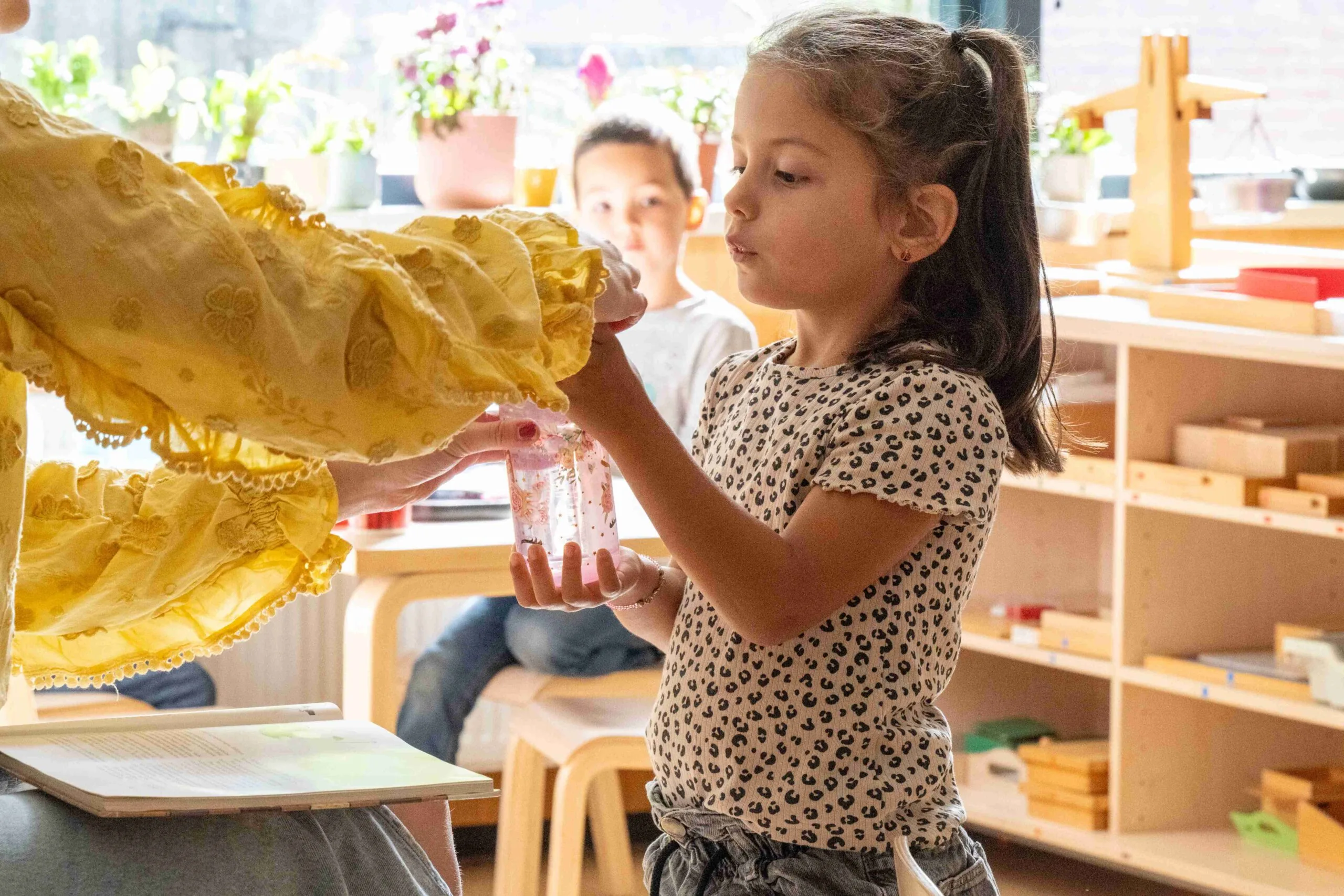 Sarı renkteki bir kumaşı dikkatle inceleyen anasınıfı öğrencisi